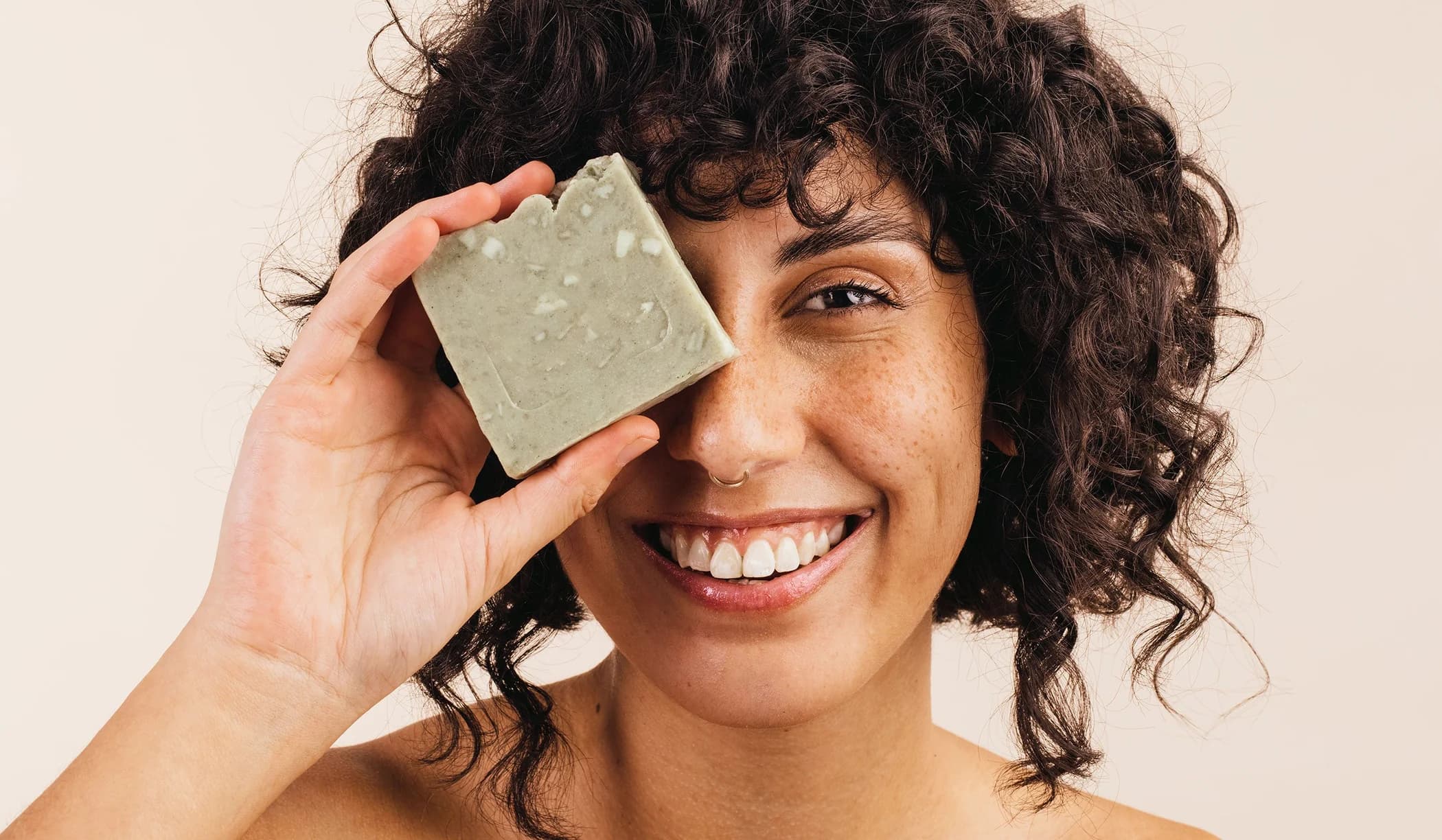 Customer holding a cleansing balm bar in front of her eye